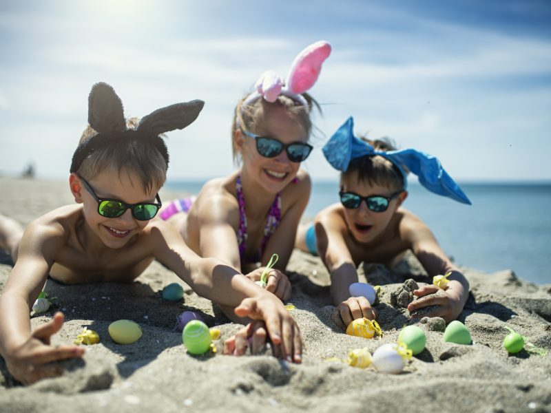 Summer Easter on beach. Kids are lying on hot sand and playing with Easter eggs.
Nikon D850