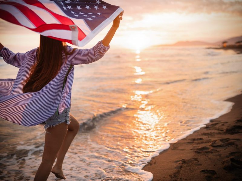 Happy woman running on beach while celebrateing independence day and enjoying freedom in USA Happy woman smiling and running on beach while celebrateing independence day and enjoying freedom in USA