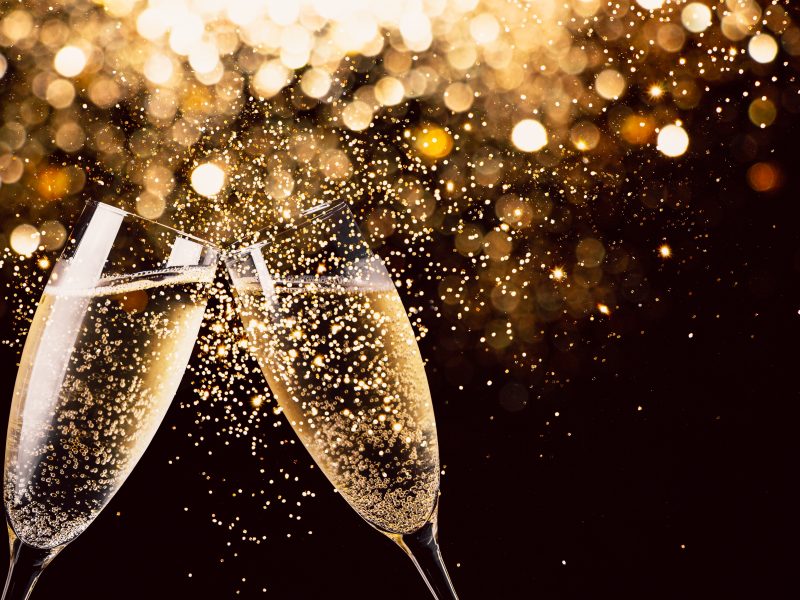 Celebration toast with champagne Two glasses of champagne toasting in the nigh with lights bokeh, glitter and sparks on the background
