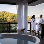 Couple on honeymoon suite soaking tub with a ocean view