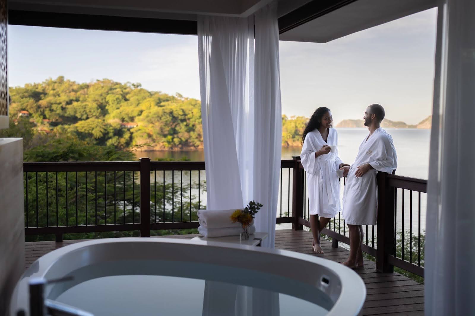 Couple on honeymoon suite soaking tub with a ocean view