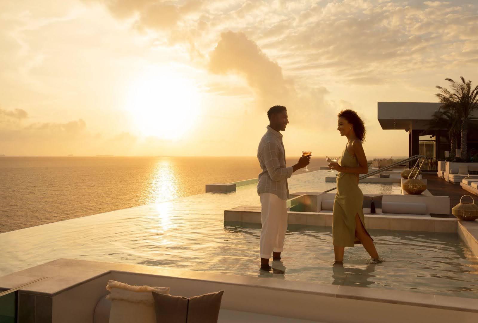 Couple toasting in the pool at sunset