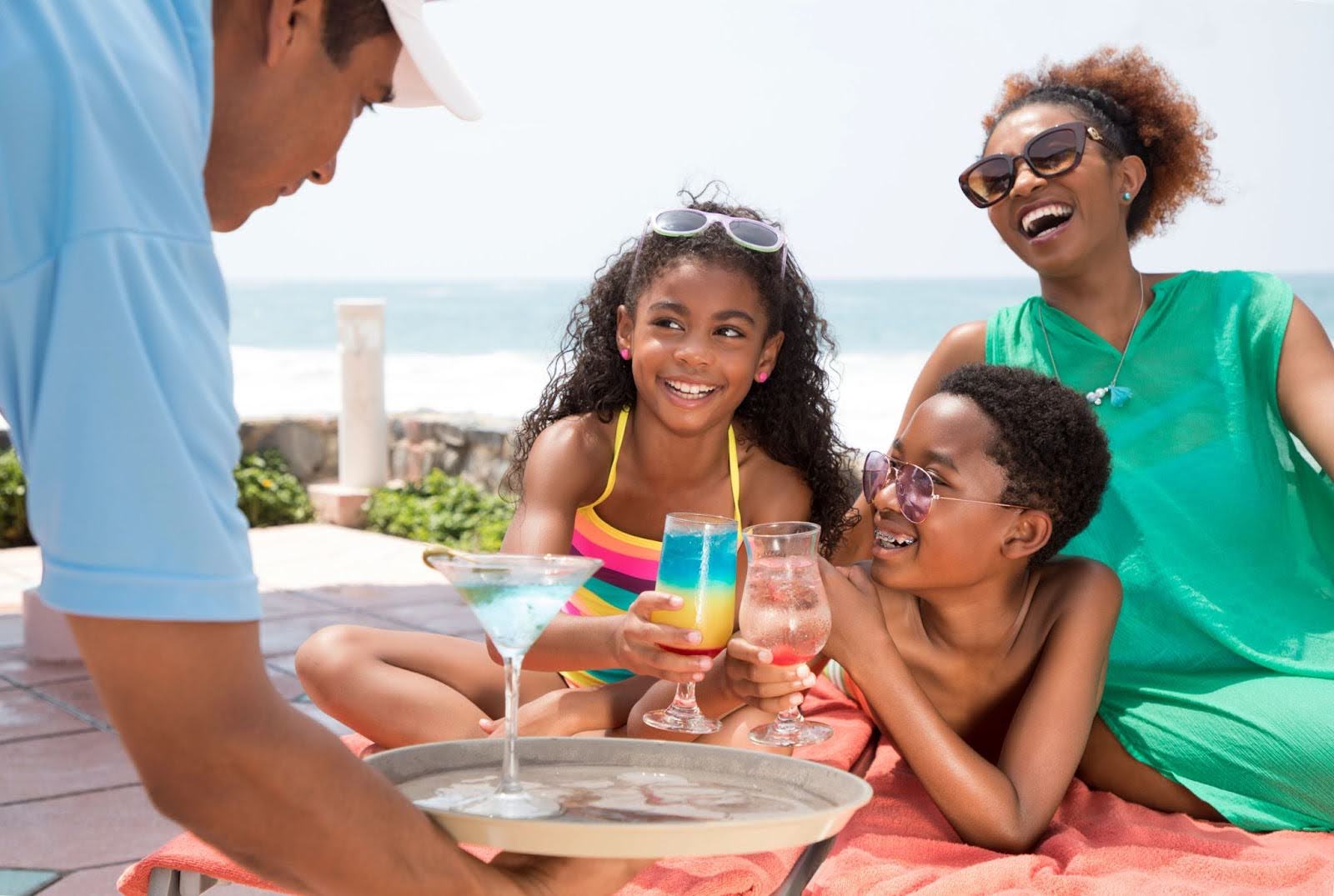 Waiter serving drinks for a family by the pool