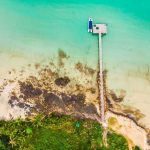 Aerial view from the sea with a pier, a boat and some rocks nearby