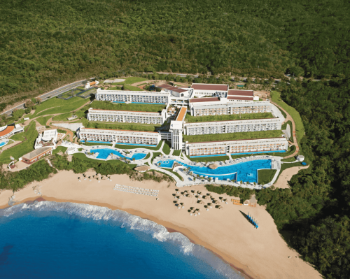 aerial view of a seaside resort surrounded by mountains and lush vegetation. secrets huatulco resort & spa.