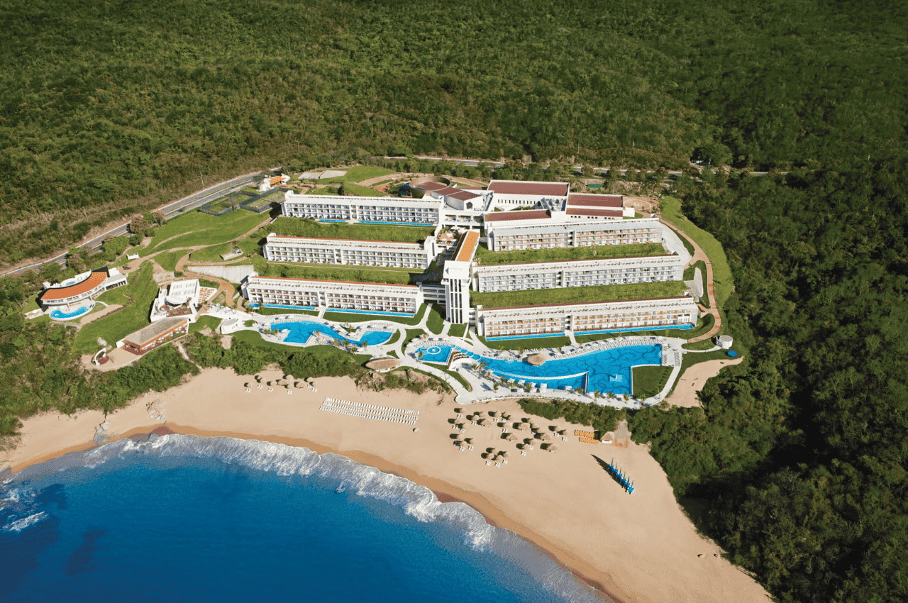aerial view of a seaside resort surrounded by mountains and lush vegetation. secrets huatulco resort & spa.