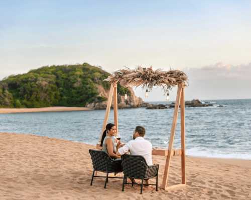 couple enjoying romantic beach dinner under rustic canopy secrets huatulco resort & spa