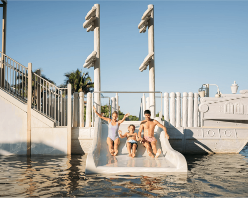 family sliding into pool at kids water park attraction dreams bahia mita surf & spa resort