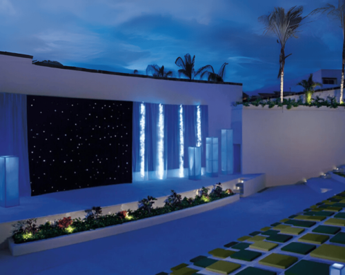 outdoor resort theater with stage lighting and tiered seating at night dreams vallarta bay resort & spa