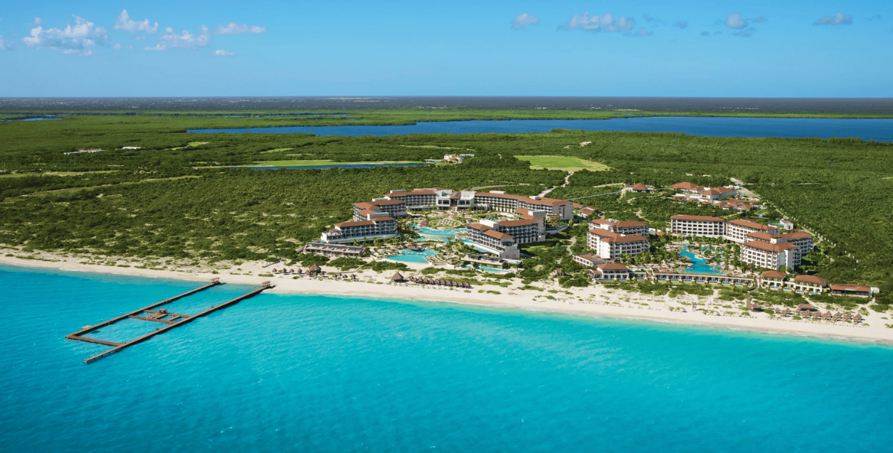 aerial view of the resort facing a white sand beach and turquoise sea secrets playa mujeres golf & spa resort.