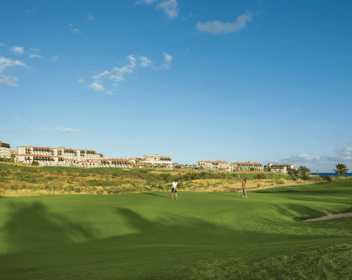 golfers playing on lush green course with resort view in the background secrets puerto los cabos golf & spa resort