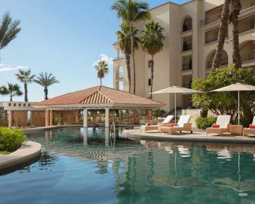 luxury resort pool with swim up bar, sun loungers and palm trees dreams los cabos suites golf resort & spa
