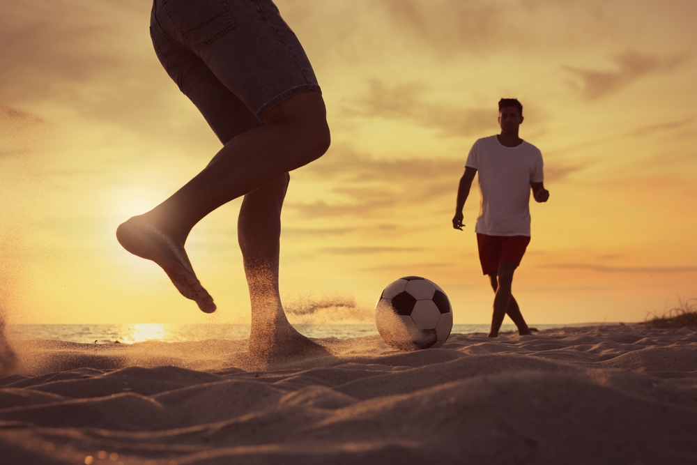 Friends,Playing,Football,On,Beach,At,Sunset,,Closeup Friends,Playing,Football,On,Beach,At,Sunset,,Closeup